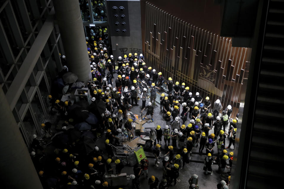 Protesters gather inside the Legislative Council building in Hong Kong, Monday, July 1, 2019. Protesters in Hong Kong took over the legislature's main building Monday night, tearing down portraits of legislative leaders and spray painting pro-democracy slogans on the walls of the main chamber.(AP Photo/Kin Cheung)