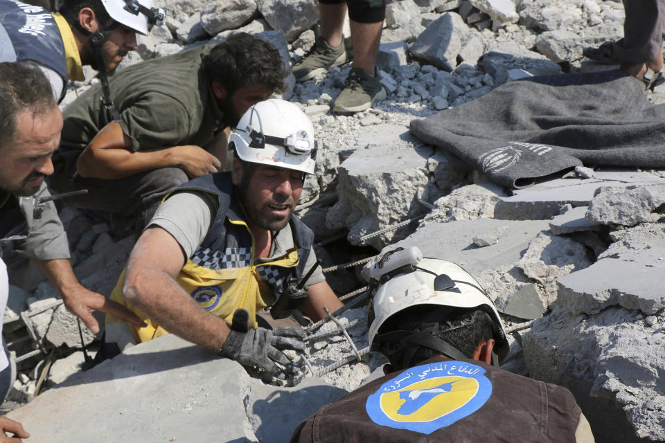 This photo provided by the Syrian Civil Defense White Helmets, which has been authenticated based on its contents and other AP reporting, shows Syrian White Helmet civil defense workers search for victims from under the rubble of a destroyed building that hit by airstrikes, in Deir al-Sharqi village, in Idlib province, Syria, Saturday, Aug 17, 2019. Syrian activists and a war monitor say airstrikes have pounded the southern edge of a rebel stronghold in the country's northwest, in one instance killing seven including children. (Syrian Civil Defense White Helmets via AP)
