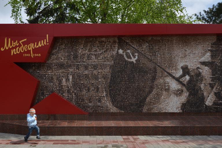 A boy runs in front of a World War II memorial panel in Stavropol on May 2, 2015 showing the famous Soviet picture "Flag above the Reichstag"