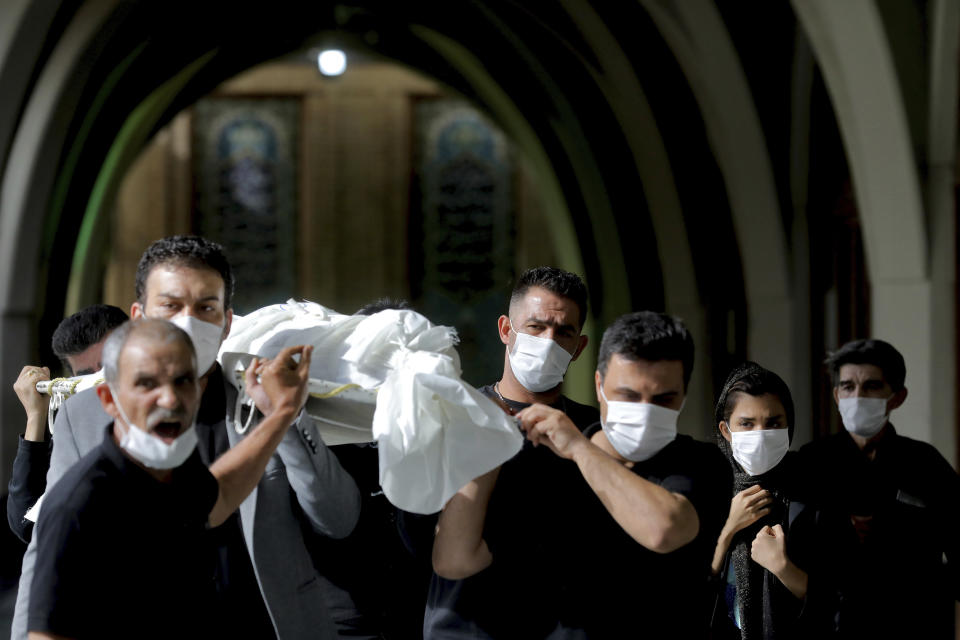 Mourners carry the body of a person who died from COVID-19 at the Behesht-e-Zahra cemetery on the outskirts of Tehran, Iran, Sunday, Nov. 1, 2020. The cemetery is struggling to keep up with the coronavirus pandemic ravaging Iran, with double the usual number of bodies arriving each day and grave diggers excavating thousands of new plots. (AP Photo/Ebrahim Noroozi)