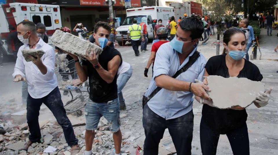 Volunteers relay debris away from the quake hit school. Source: Reuters