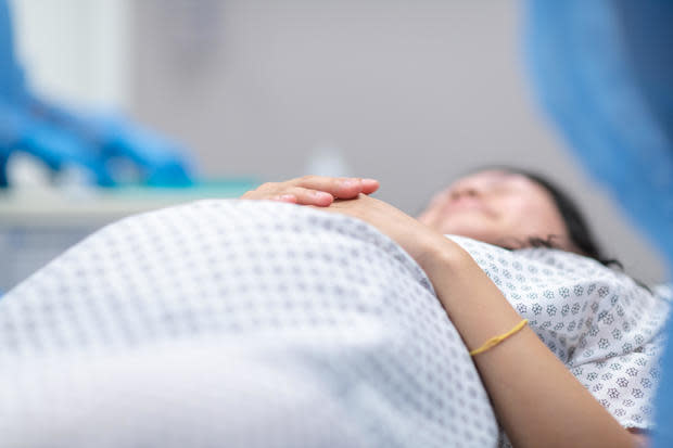 Pregnant woman lays on operating table before receiving cesarean section 