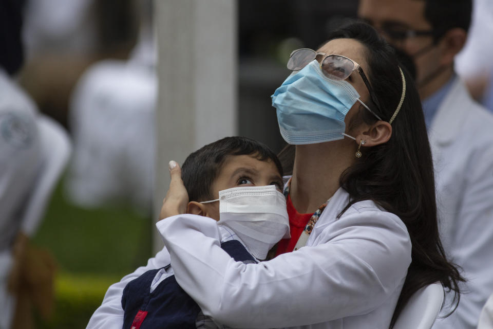 A health worker at the San Juan de Dios hospital holds a child during a minute of silence in memory of her colleagues who have fallen victim to COVID-19 in Guatemala City, Friday, Oct. 9, 2020. (AP Photo/Moises Castillo)