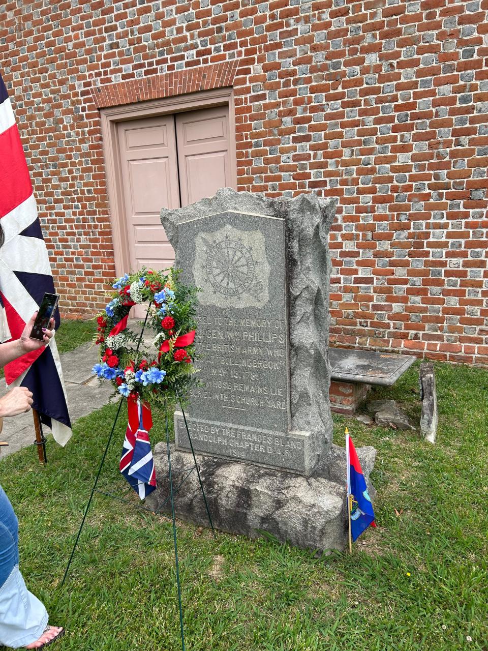 A marker honoring the late Maj. Gen. William Phillips is adorned with British flags and a wreath Saturday, May 13, 2023 at Blandford Church in Petersburg. Saturday marked the 242nd anniversary of Phillips’ death during the Battle of Petersburg in the American Revolution. He is the highest-ranked English officer not buried in British soil.