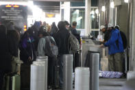 Travelers queue up at the Southwest Airlines curbside check-in area at Denver International Airport Sunday, Dec. 26, 2021, in Denver. Airlines cancelled hundreds of flights Sunday, citing staffing problems tied to COVID-19 to extend the nation's travel problems beyond Christmas. (AP Photo/David Zalubowski)