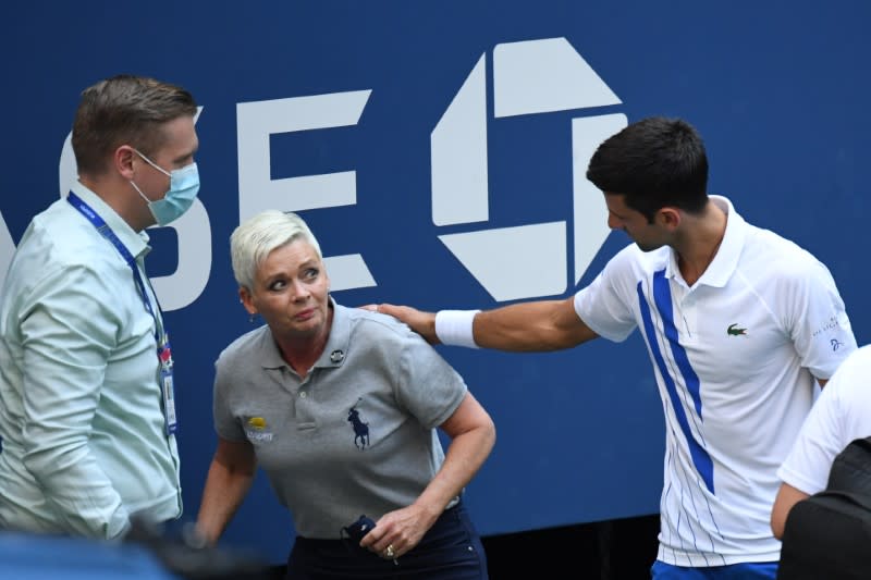 El tenista serbio Novak Djokovic y autoridades del torneo asisten a una jueza de línea que fue golpeada por una pelota de Djokovic