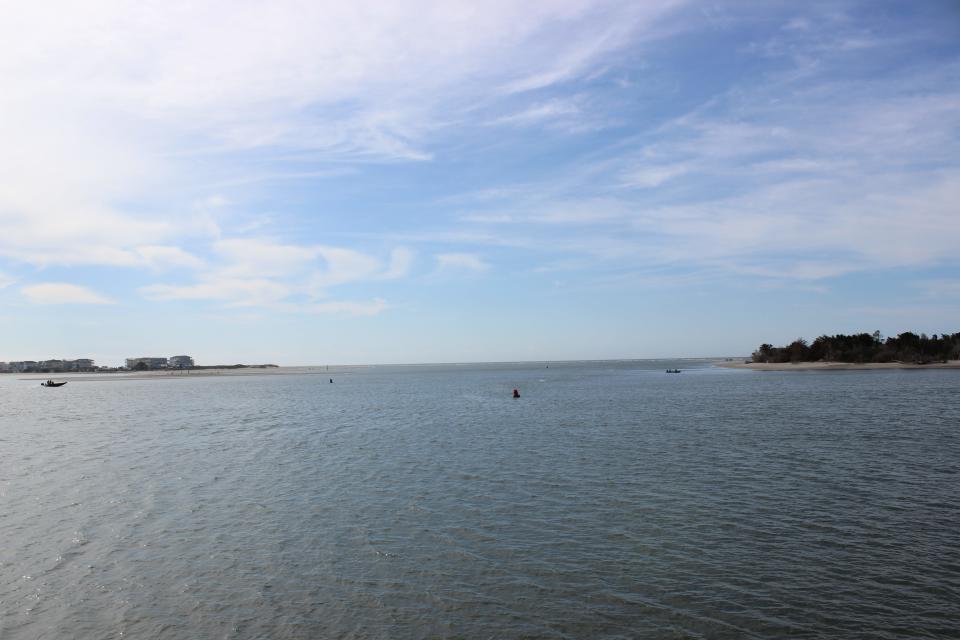 Small boats navigate the Lockwood Folly Inlet between Oak Island and Holden Beach on Friday, March 17, 2023.