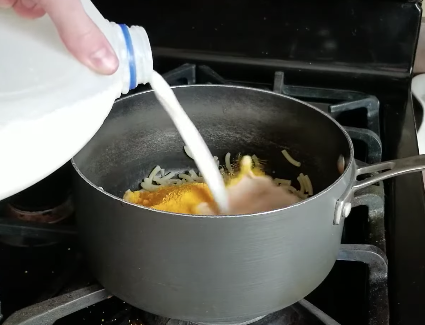 Adding milk to saucepan of Kraft mac 'n' cheese on the stove