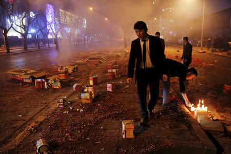 FILE PHOTO: People make sure that all firecrackers and fireworks have exploded during celebrations for the start of the Chinese Lunar New Year of Monkey in Beijing, China February 7, 2016. REUTERS/Damir Sagolj/File Photo