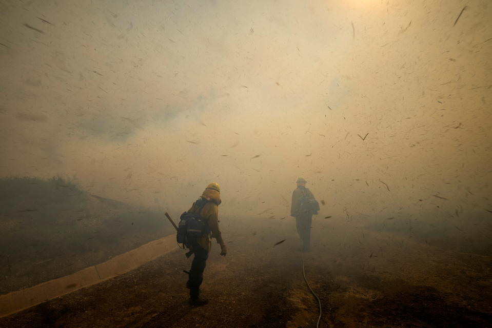 Firefighters face strong winds as they head up a hillside to battle a wind driven wildfire near Irvine, California.