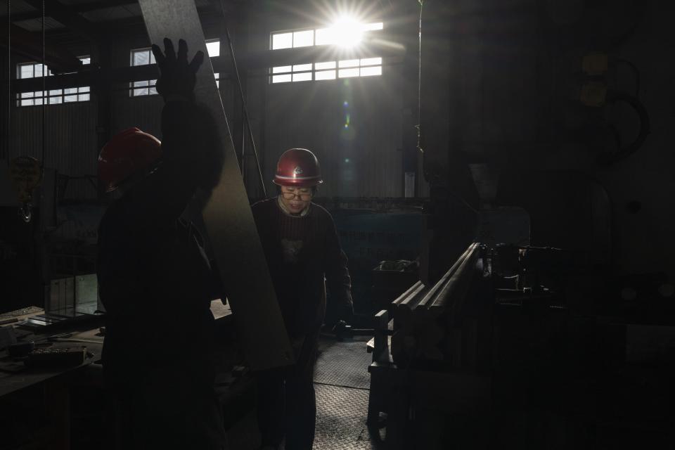 Workers cut metal parts at a factory that produces many things including brackets for rooftop solar panels in the rural outskirts of Jinan in eastern China's Shandong province on March 21, 2024. (AP Photo/Ng Han Guan)