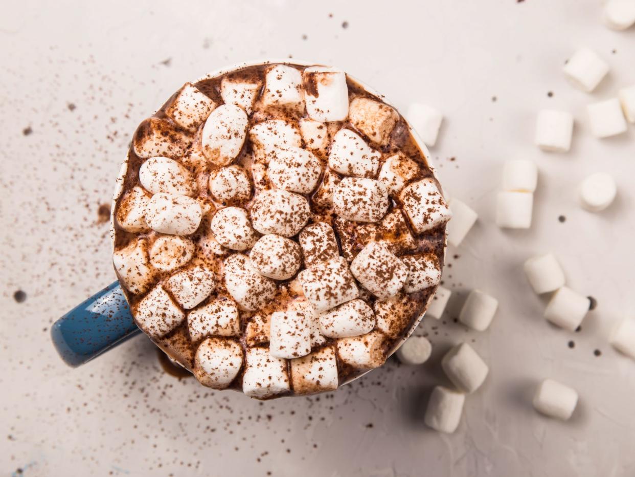 Cocoa marshmallows sprinkled with cocoa from above on a winter hot drink. Top view, flat lay.