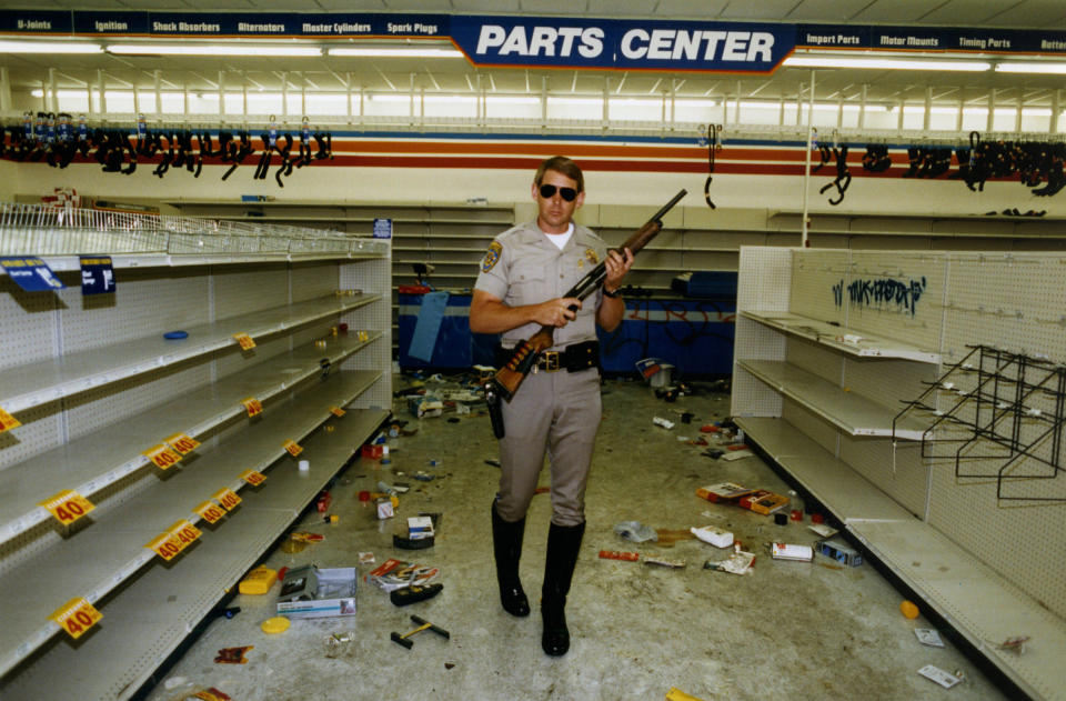 Officer Hugh Gnecco of the California Highway Patrol checks for looters in an auto parts store at Washington Boulevard and Western Avenue during the L.A. riots on May 1, 1992.<span class="copyright">Rick Meyer—Los Angeles Times/Getty Images</span>