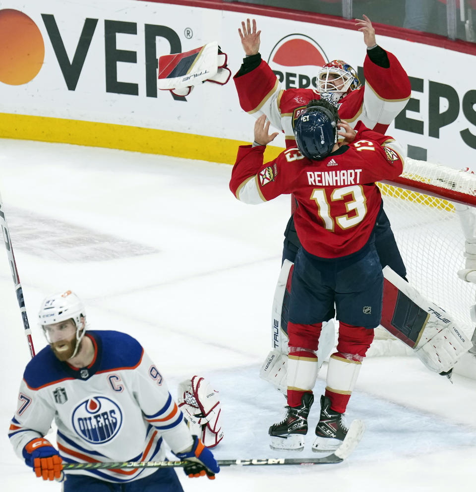 Florida Panthers goaltender Sergei Bobrovsky, top, and forward Sam Reinhart (13) celebrate after winning the NHL hockey Stanley Cup as Edmonton Oilers forward Connor McDavid (97) looks on after Game 7 of the Final in Sunrise, Fla., Monday, June 24, 2024. (Nathan Denette/The Canadian Press via AP)