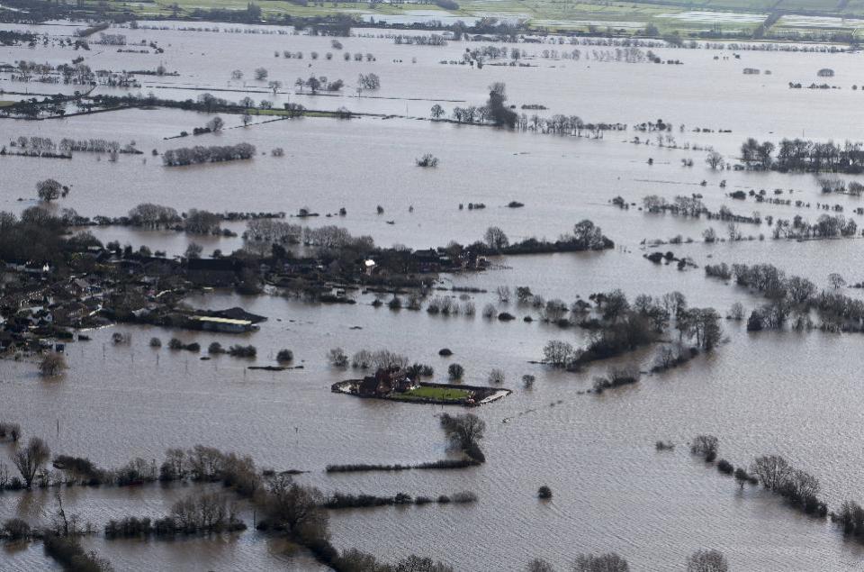 Flood waters inundate the area as one home stands alone and dry near the flooded village of Moorland in Somerset, southwest England, Thursday Feb. 13, 2014. The house is owned by Sam Notaro, who has built his own levee to hold back the flood waters, as the local communities face further misery in the coming days with heavy rain, wind and snow predicted to sweep across Britain. (AP Photo/Steve Parsons, PA) UNITED KINGDOM OUT - NO SALES - NO ARCHIVES