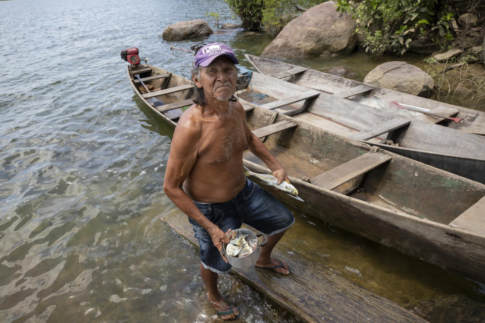 El pescador Ginoca Trindade mira a cámara mientras prepara las capturas del día en la orilla del río Xingu, cerca de la presa hidroeléctrica de Belo Monte en Altamira, en el estado brasileño de Para, el viernes 6 de septiembre de 2019. Trindade, que lleva más de 50 años viviendo y pescando en el río Xingu, dijo que tras la construcciónd e la presa solo pesca unas pocas libras de pescado cada dos días, frente a las 70 libras (30 kilos) que pescaba en dos días antes de que se levantara la presa. (AP Foto/Andre Penner)