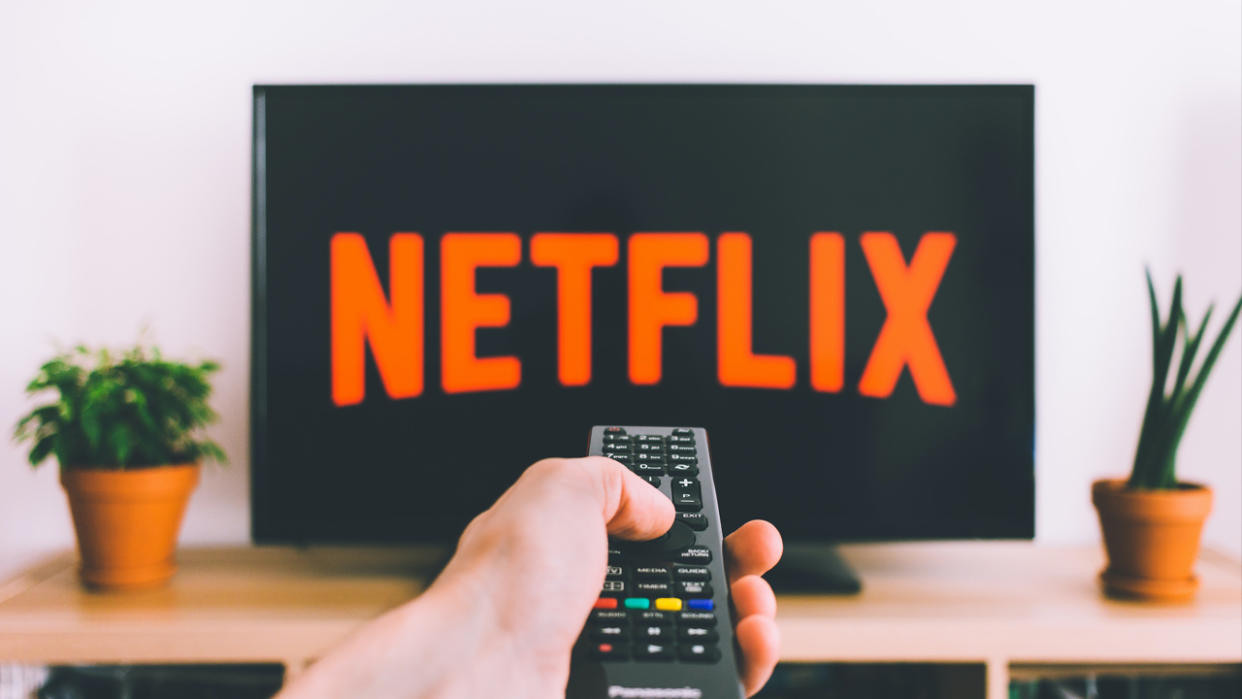  A remote control pointing at a TV displaying the Netflix logo. 