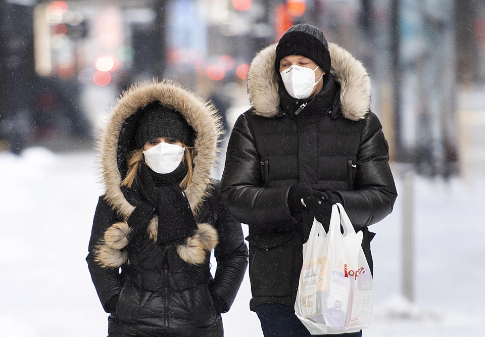 People wear face masks as they walk along a street in Montreal, Saturday, Jan. 23, 2021, as the COVID-19 pandemic continues in Canada and around the world. (Graham Hughes/The Canadian Press via AP)