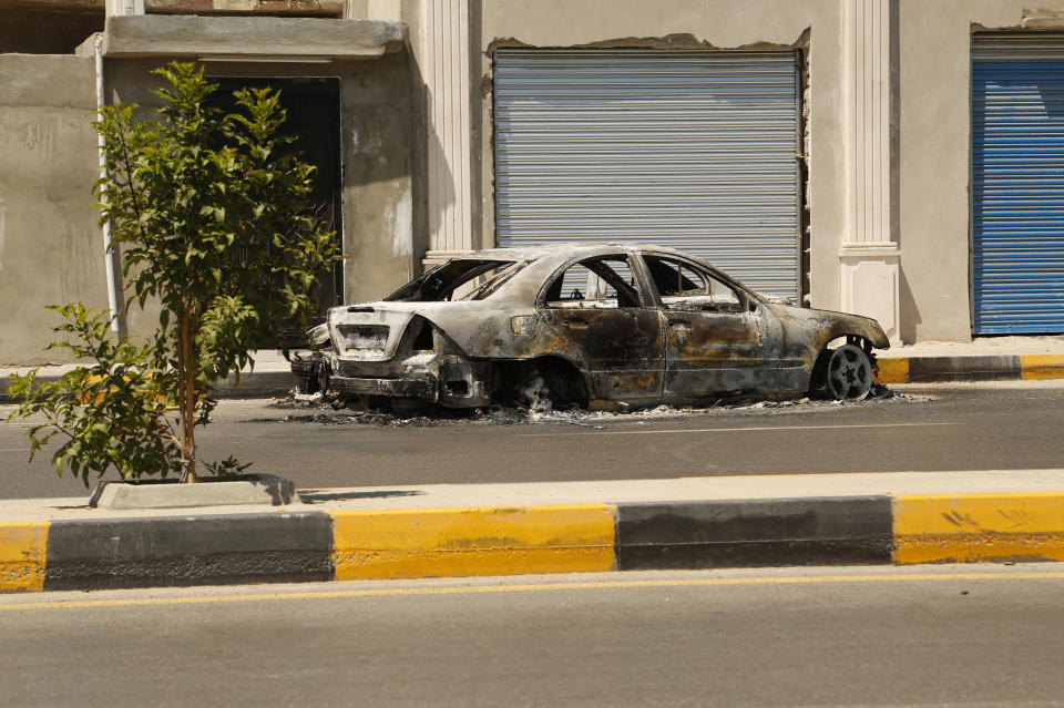 The remains of a car damaged in clashes stands in a street in the Libyan capital of Tripoli on Friday, July 22 2022. One of Libya’s rival governments on Friday called on militias to stop fighting, after clashes broke out in the country’s capital, Tripoli overnight, killing at least one civilian and forcing around 200 people to flee the area (AP Photo/Yousef Murad)