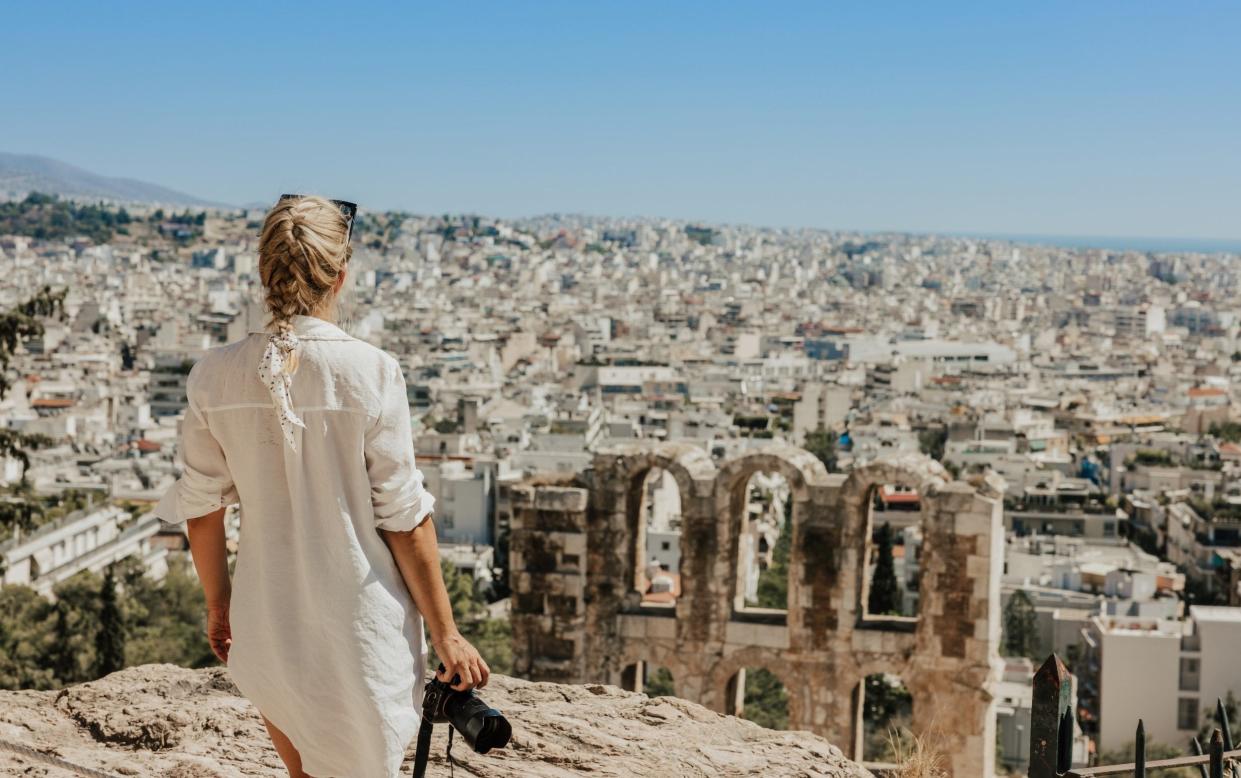 Woman with camera looking at ancient Theater Of Herodes Atticus