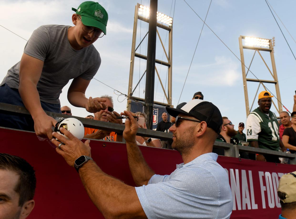 Enshrinee Joe Thomas signs a ball for a fan Thursday before the start of 2023 Hall of Fame Game between Cleveland Browns and New York Jets at Tom Benson Hall of Fame Stadium.