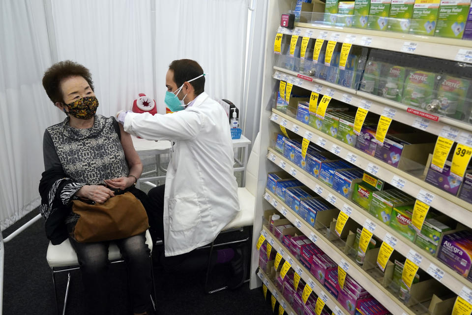 FILE - Pharmacist Todd Gharibian, right, administers a dose of the Moderna COVID-19 vaccine to Toshiko Sugiyama, left, at a CVS Pharmacy branch on March 1, 2021, in Los Angeles. A rush of vaccine-seeking customers and staff shortages are squeezing drugstores around the country. That has led to frazzled workers and even temporary pharmacy closures. (AP Photo/Marcio Jose Sanchez, File)