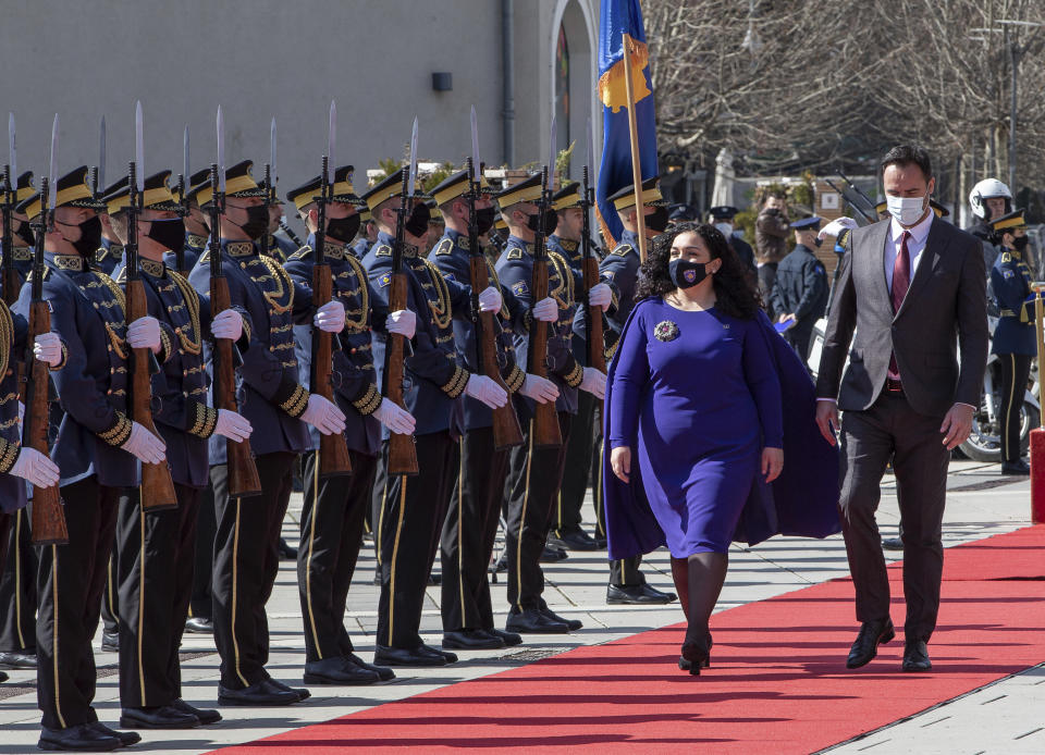 Kosovo newly elected president Vjosa Osmani-Sadriu, center, flanked by speaker of parliament Glauk Konjufca, inspect the Guard of Honour during a presidential hand over ceremony in capital Pristina, Kosovo, on Tuesday, April 6, 2021. Osmani took over the presidency after being elected to the post during a two-day extraordinary session of parliament. (AP Photo/ Visar Kryeziu)