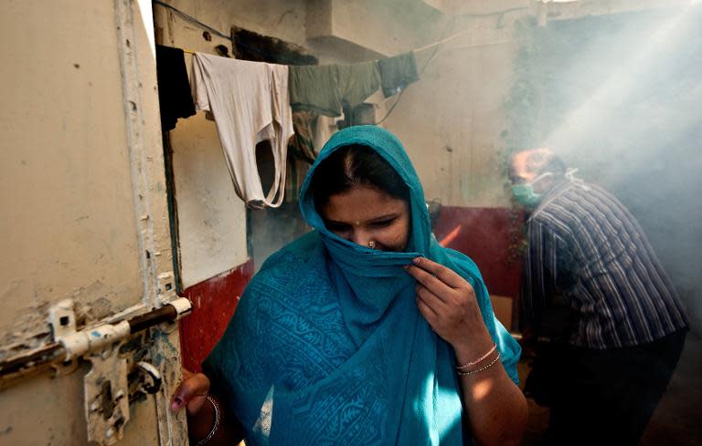 A woman covers her face as a municipal health worker fumigates against mosquitoes at a neighborhood in New Delhi, on October 3, 2013