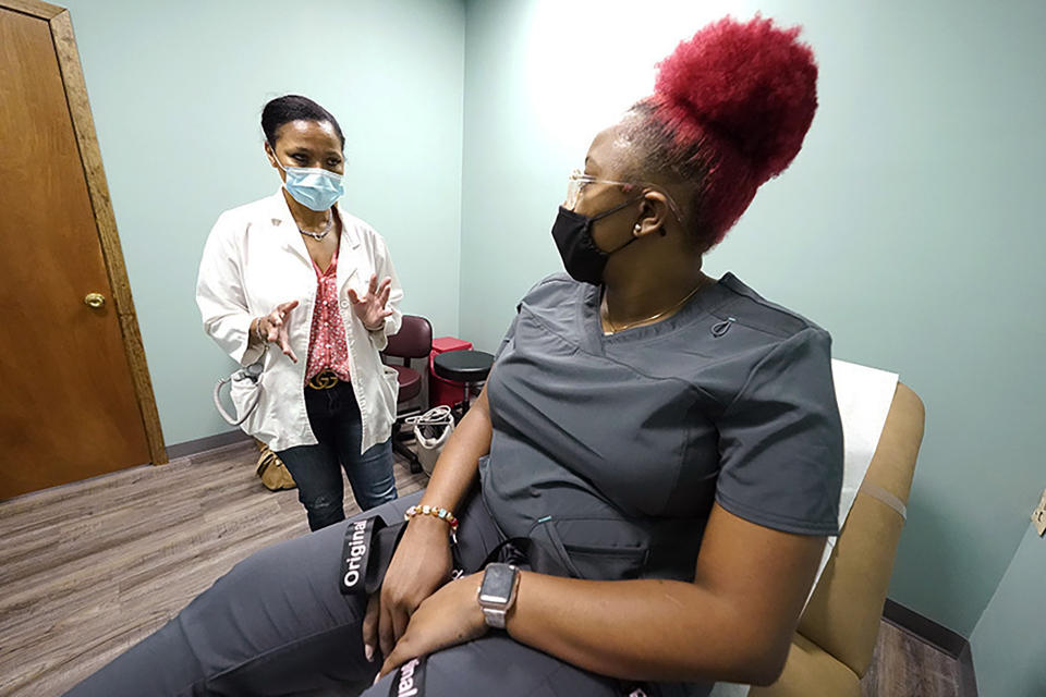 Dr. Felecia Brown, a midwife at Sisters in Birth, a Jackson, Miss., clinic that serves pregnant women, left, confers with Kamiko Farris, of Yazoo City, following use of a Doppler probe to measure the heartbeat of her fetus, Dec. 17, 2021. (AP Photo/Rogelio V. Solis)