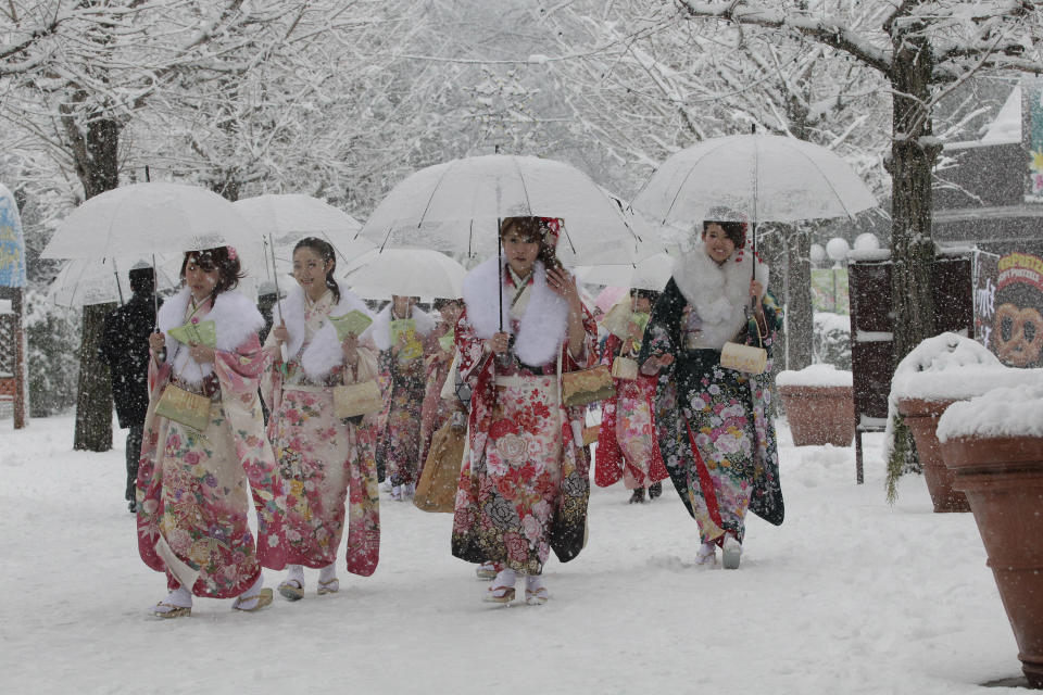 Dressed in Japanese kimonos, Japanese youths who have turned or will turn 20-year-old this year, the traditional age of adulthood in Japan, walk in the snow following a Coming of Age ceremony at an amusement park in Tokyo Monday, Jan. 14, 2013. (AP Photo/Shizuo Kambayashi)