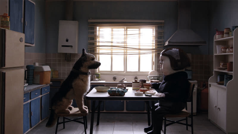 A woman sits across the table from a dog