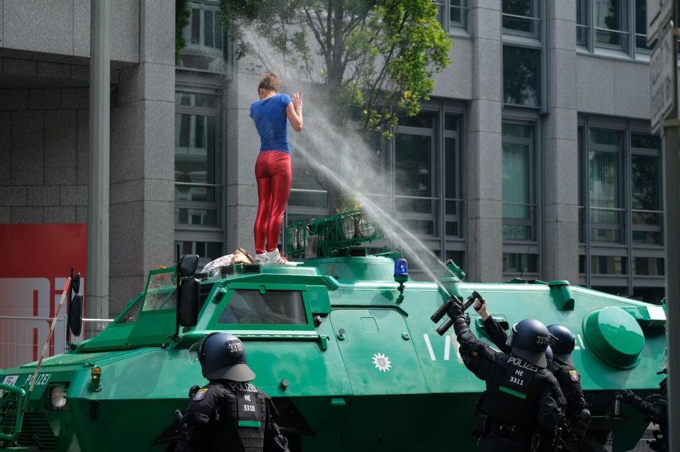 Policemen shoot pepper spray on a demonstrator who has climbed onto an armored vehicle.