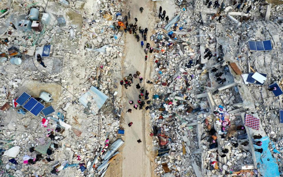 People search for survivors amidst the rubble of collapsed buildings in Besnia in Syria - OMAR HAJ KADOUR/AFP