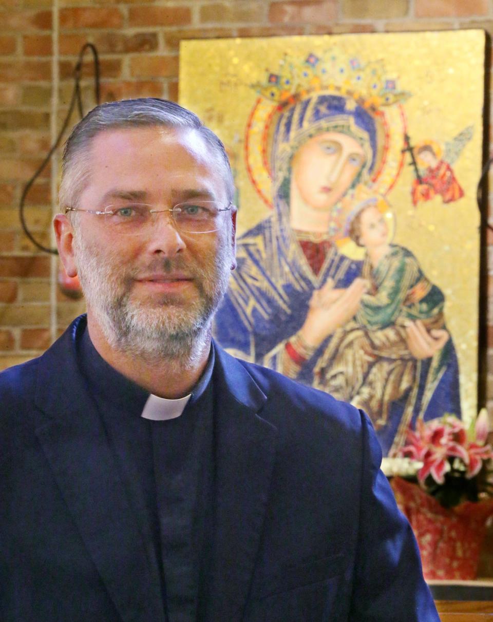 Rev. Shawn Conoboy stands with the icon of Our Lady of Perpetual Help in the sanctuary of the church in Aurora on Friday.  Rev. Conoboy is going to the Vatican to work on the staff of Dicastery for Promoting Integral Human Development.