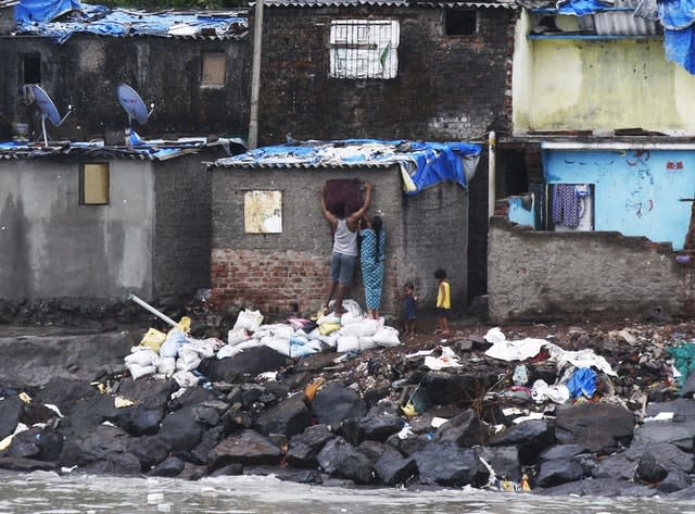 A fisherman’s family seals up a window before cyclone Nisarga strikes (Rajanish Kakade/AP)