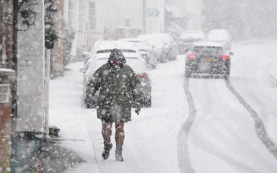 A person walking through a snow flurry in Lenham, Kent