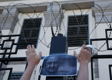 A man hangs a picture of Russian dissident journalist Arkady Babchenko, who was shot dead in the Ukrainian capital on May 29, on a fence of the Russian embassy in Kiev, Ukraine May 30, 2018. REUTERS/Gleb Garanich