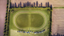 <p>A perfectly oval running track is surrounded by trees, as seen from far above.</p>