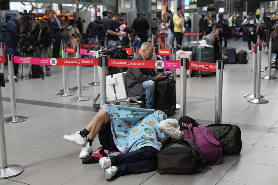 Pasajeros de Viva Air duermen junto a sus maletas luego de que la aerolínea de bajo costo suspendiera sus operaciones en el Aeropuerto Internacional El Dorado de Bogotá, Colombia, el martes 28 de febrero de 2023. (AP Foto/Fernando Vergara)