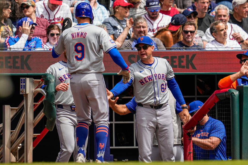 New York Mets left fielder Brandon Nimmo (9) reacts with manager Carlos Mendoza (64) after scoring a run against the Atlanta Braves during the second inning on April 11, 2024, at Truist Park.