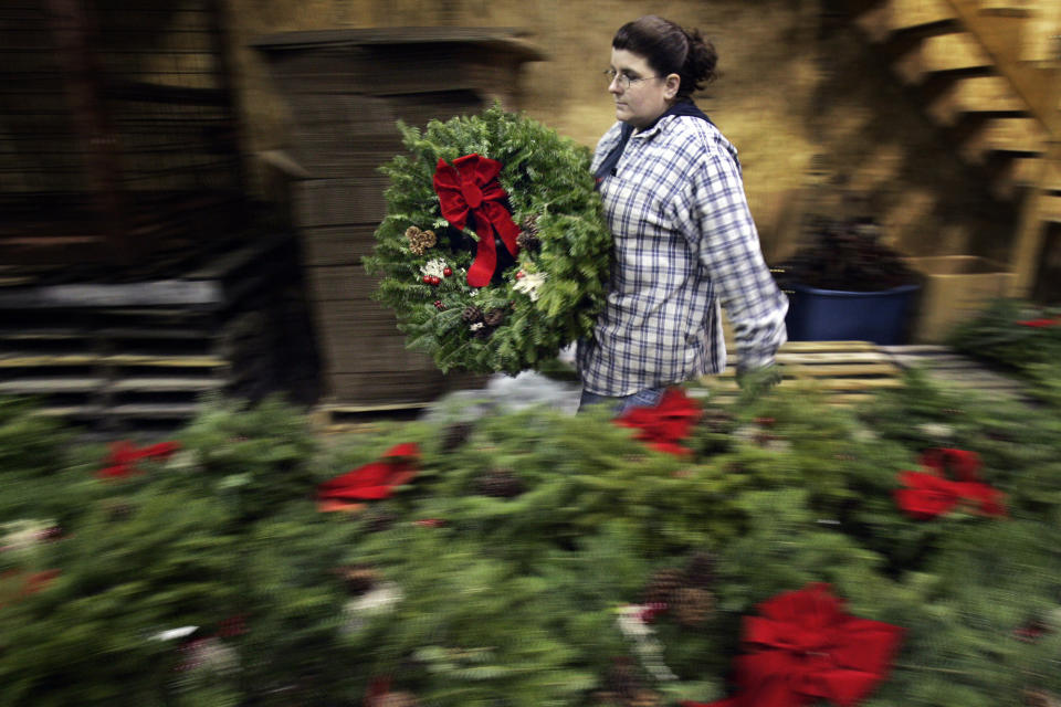 FILE - Jill Parritt carries a finished wreath at the Worcester Wreath company in Harrington, Maine, in this Dec. 1, 2006 file photo. The family that started the Wreaths Across America program wants to build the world's largest flagpole and a theme park honoring the country's veterans in Down East Maine. (Photo/Robert F. Bukaty, File)