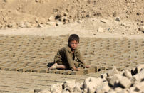 <p>An Afghan boy at a brick kiln piles up new bricks, in Kabul, Afghanistan on September 26, 2016. (Hedayatullah Amid/ EPA)</p>