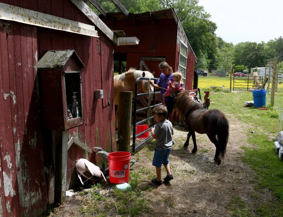 Tabatha Roberts, owner of Funny Farm Petting Zoo, with her children Carson, left, and Savannah get ready to ride a pony May 19, 2023, in Berlin, Maryland.