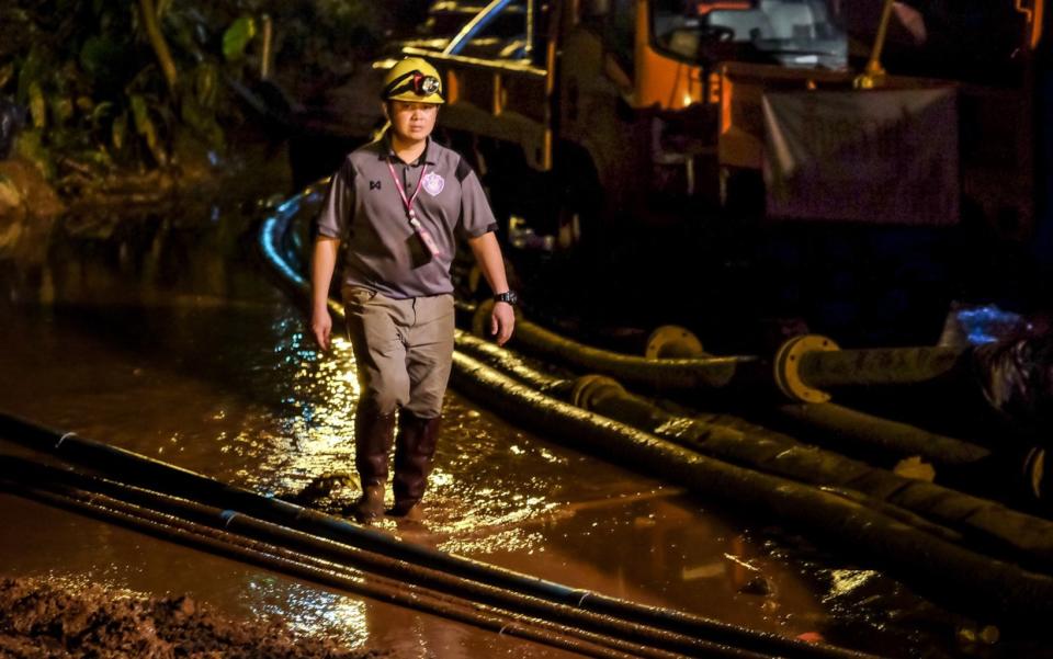 A rescuer worker walks between the hoses which are carrying water out of Tham Luang Nang Non cave on July 5, 2018 in Chiang Rai, Thailand, where rescue crews are working to retrieve 12 boys and their soccer coach after nearly two weeks trapped in a cave. Videos released by the Thai Navy SEAL shows the boys, aged 11 to 16, and their 15-year-old and the challenge now will be to extract the party safely. <cite>Linh Pham/Getty</cite>