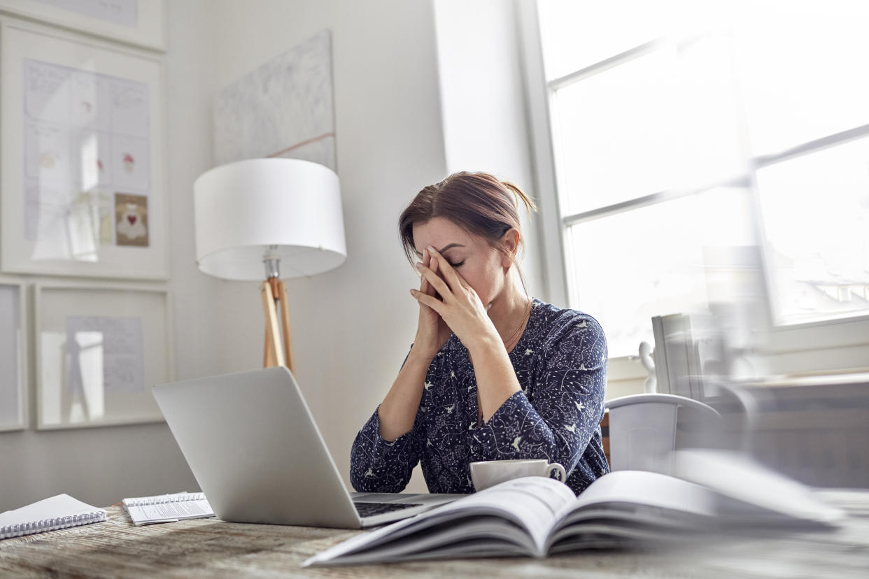 Tired, stressed businesswoman at laptop with head in hands