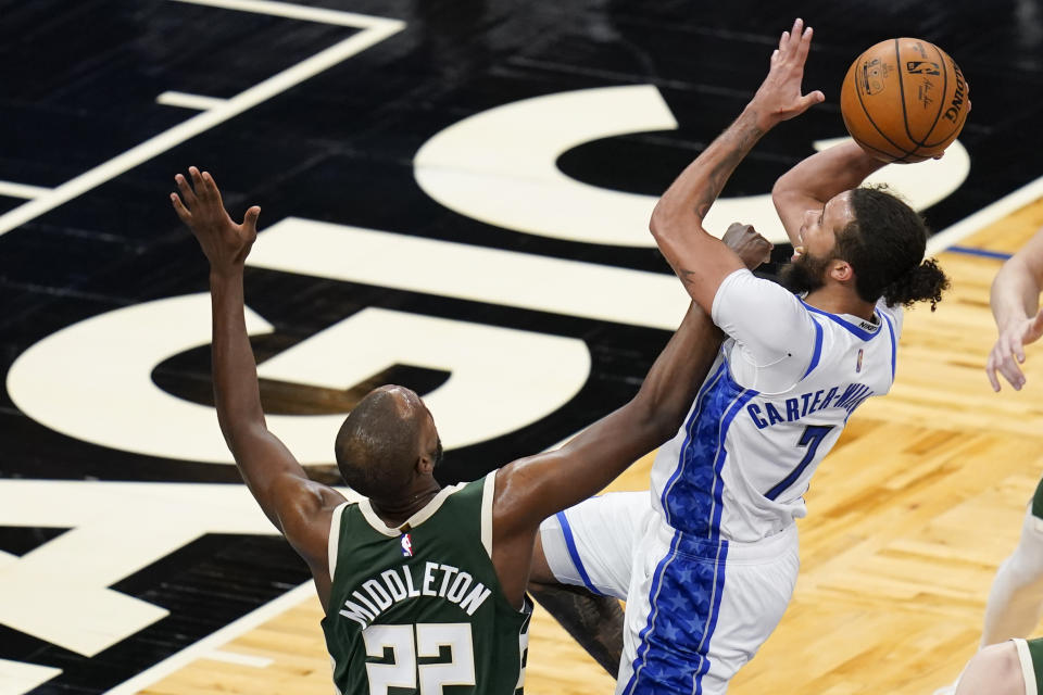 Milwaukee Bucks forward Khris Middleton (22) tries to stop Orlando Magic guard Michael Carter-Williams (7) as he takes a shot during the second half of an NBA basketball game, Sunday, April 11, 2021, in Orlando, Fla. (AP Photo/John Raoux)