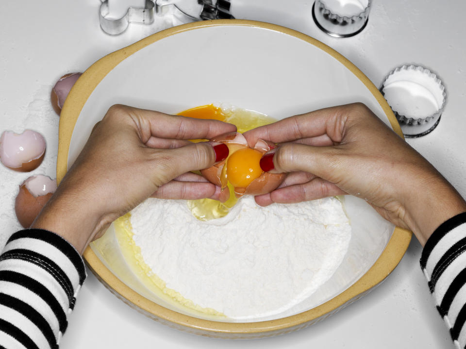 Cracking egg yolk into bowl.