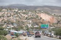 Vehicles drive along the road as Canaan in seen in the background, on the outskirts of Port-au-Prince