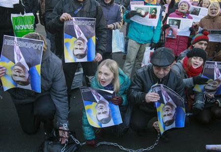 Protesters hold upturned portraits of Ukrainian President Viktor Yanukovich and journalist Tetyana Chornovil, who was beaten and left in a ditch just hours after publishing an article on the assets of top government officials, during a protest rally in front of the Ukrainian Ministry of Internal Affairs in Kiev, December 26, 2013. The text on the portraits reads "Upturn" (which in Ukrainian is synonymous with coup). REUTERS/Gleb Garanich