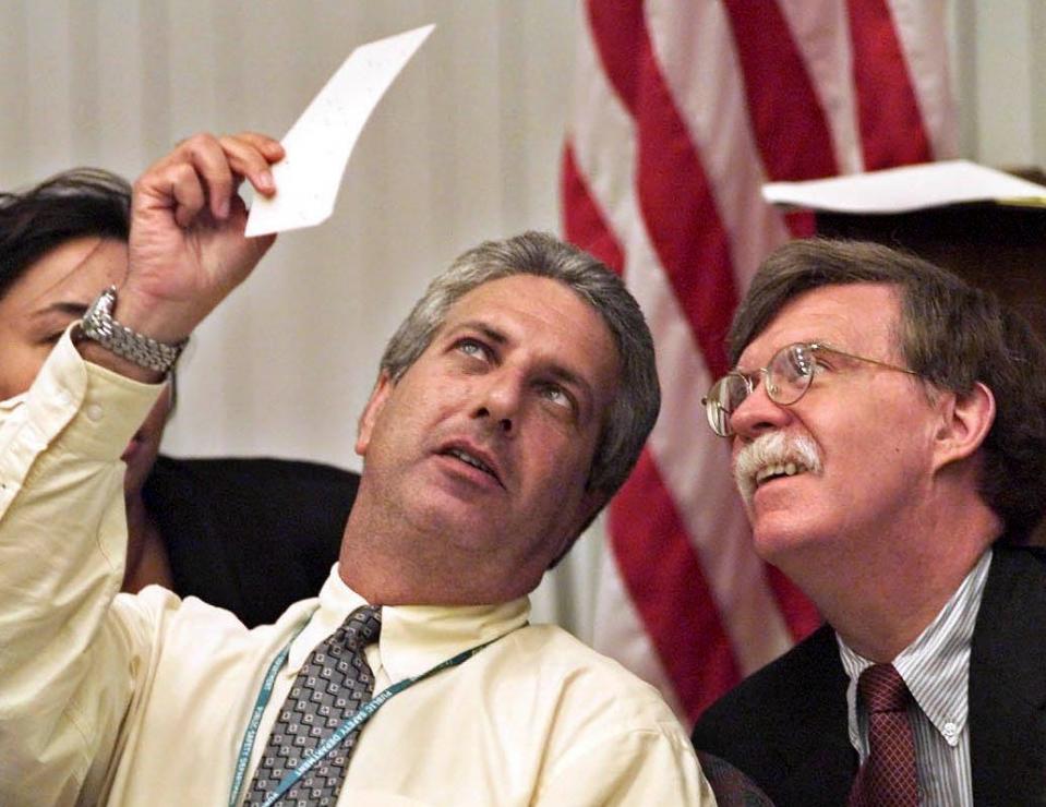 Palm Beach County Election Canvassing Board Chairman Charles Burton holds up one of thousands of questionable ballots next to Republican attorney John Bolton during recounts in the aftermath of the 2000 presidential election.